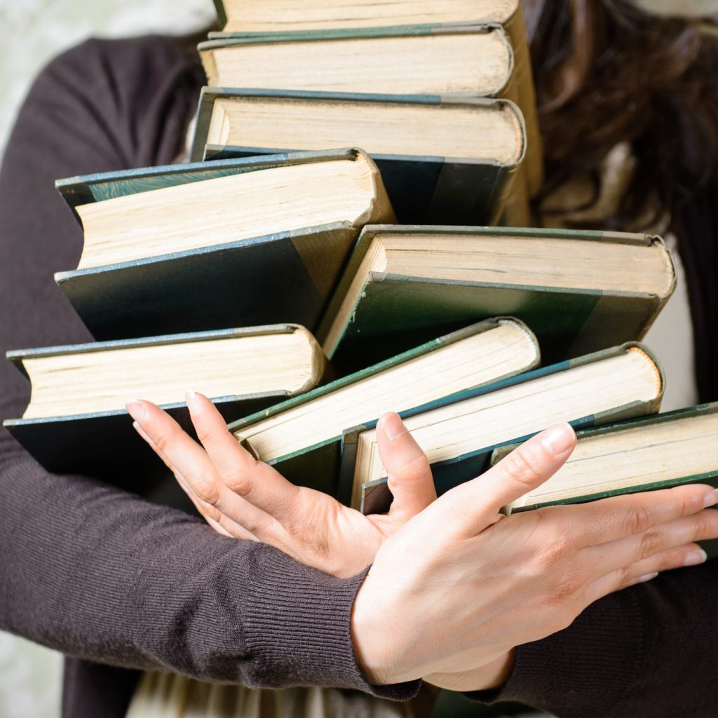 Many books clutched in womans arms